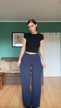 Marineblauwe wijde broek gemaakt van een gladde stof, met een hoge taille en plooien aan de voorkant; gedragen met een aansluitend zwart top.