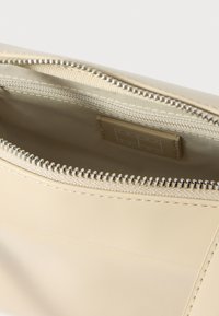 Μπεζ τσάντα με φερμουάρ και εξωτερικό από λείο δέρμα, με ασημένιο φερμουάρ και εσωτερική επένδυση. Απλός σχεδιασμός, χωρίς ορατά σχέδια ή λογότυπα.