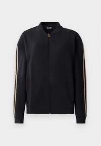 Zwarte zip-up jack met beige strepen op de mouwen, geribbelde manchetten en kraag, en een gouden rits, weergegeven op een witte achtergrond.