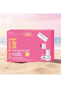 Boîte rose de la trousse basique Alessandro Striplac UV pour ongles sur une plage de sable avec images du produit et texte édition été.