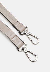 Gråtexturerad läderrem med silverfärgade metallklipp, med detaljer i sömnad och en slät yta. Justerbar längd för mångsidighet.