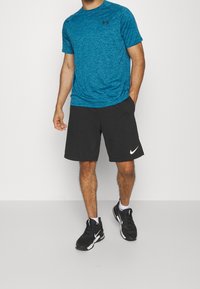 Modré melírované sportovní tričko, černé kraťasy s bílým logem Nike a černé sportovní boty. Krátké rukávy, volný střih a lehký materiál.