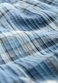 Tissu léger aux tonalités bleues avec des rayures horizontales et verticales. Texture douce, présentant un mélange de teintes claires et foncées.
