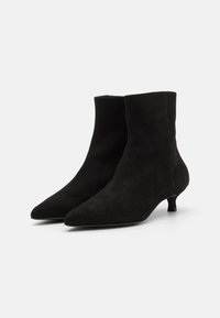 Botine negre din suede, cu vârful ascuțit și toc mic tip kitten heel. Textură netedă cu un design elegant și minimalist. Fără accesorii sau detalii vizibile.