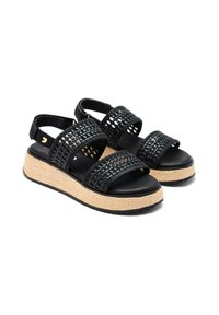 Sandalias tejidas negras con tres correas y una suela elevada de yute trenzado. La parte inferior tiene un agarre de goma texturizada.