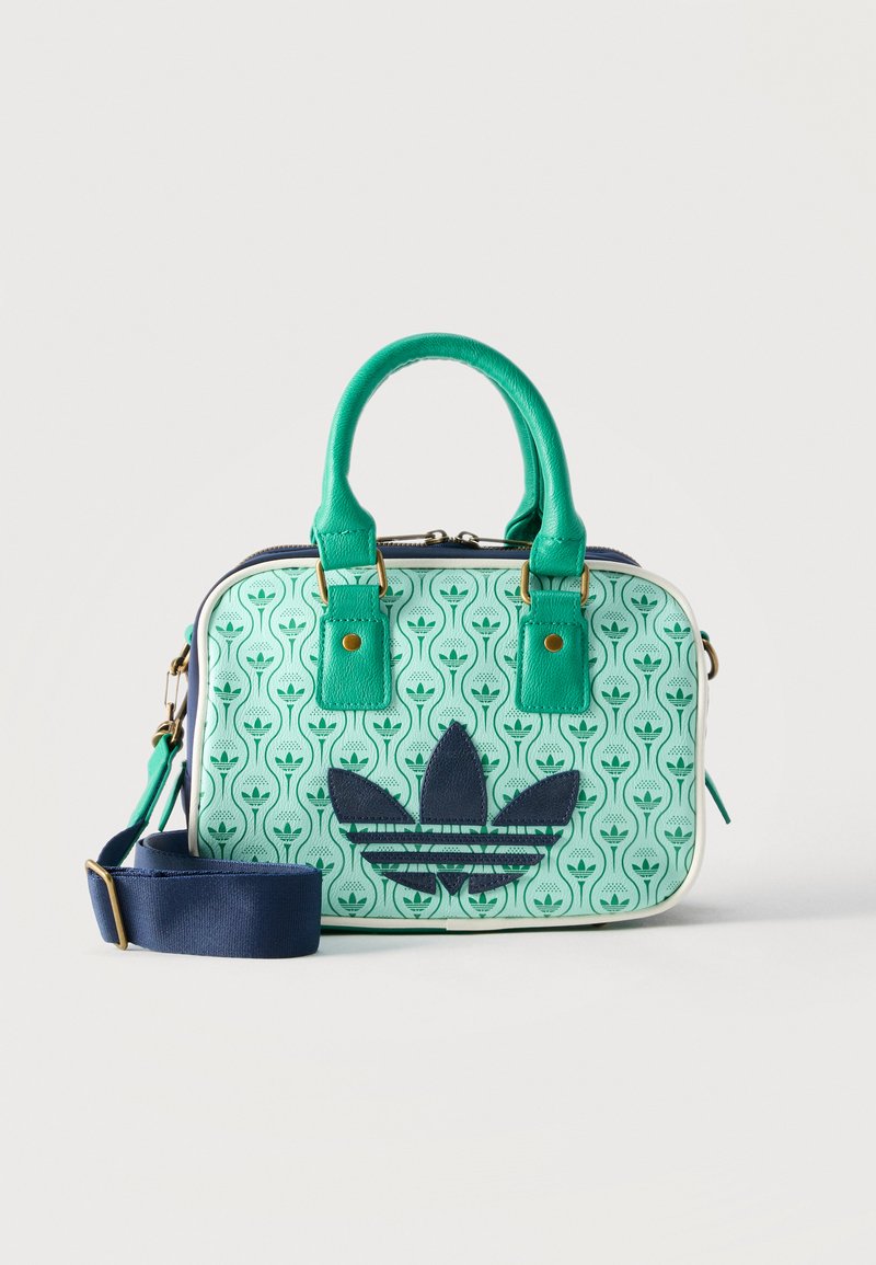 Μικρή ορθογώνια γυναικεία τσάντα με λαβές από πράσινο δέρμα, μπλε ρυθμιζόμενο ιμάντα ώμου και ανοιχτό πράσινο σώμα με σχέδιο που διαθέτει μεγάλο ναυτικό λογότυπο.