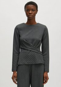Grijze lange mouwen top met verticale pinstrepen, gestructureerd design en een gewikkeld taille-effect, gecombineerd met bijpassende grijze broeken.