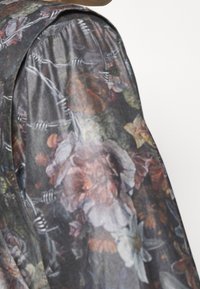 Der blumenbedruckte Stoff zeigt Schattierungen von Dunkelgrau, mit gedeckten Farben und einem kontrastierenden Stacheldrahtmuster. Die Textur ist glatt und leicht.