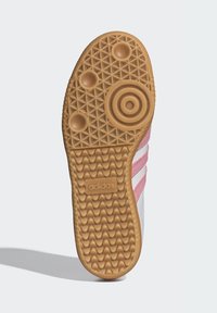 Podrážka tenisky Adidas z materiálu gumovej gumy, so vzorovanou textúrou, kruhovými a oválnymi trakčnými prvkami a ružovými pruhovanými akcentmi.