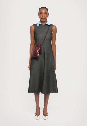 Vestido gris sin mangas con una textura sutil y falda acampanada, combinado con una camisa de cuello azul claro y un bolso cruzado burdeos. Zapatos de tacón blanco.