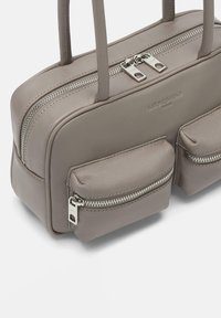 Szara skórzana torba z dwoma przednimi kieszeniami na zamek, gładka faktura, podwójne uchwyty na górze oraz metalowe wykończenia w kolorze srebrnym. Dodatkowy zamek na górze.