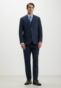 Completo a scacchi blu navy con rever a punta, chiusura a un bottone e pantaloni abbinati. Camicia elegante azzurro chiaro e scarpe eleganti nere.