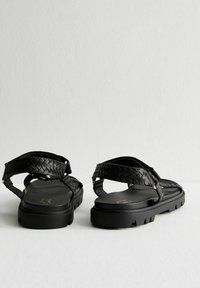 Zwarte sandalen met een textuurgeweven band, platte zool, gespsluiting en rubberen loopvlak. Glad voetbed en minimalistisch ontwerp.