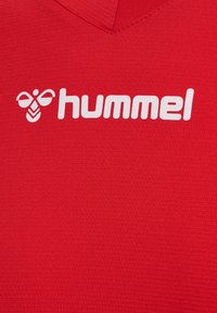Rotes Sportshirt aus strukturiertem Stoff, mit V-Ausschnitt und einem weißen Logo mit einer Biene sowie dem Wort "hummel."