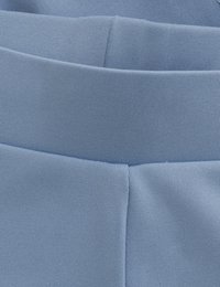 Ljusblått tyg, som visar en slät textur med en ribbad midja. Designen har rena linjer och en figurnära passform.