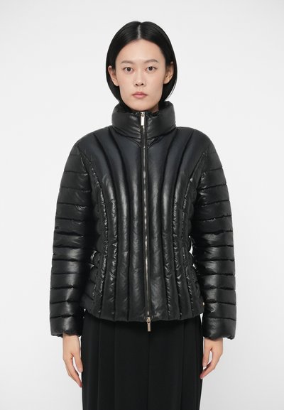 Veste matelassée noire avec un col montant, fermeture éclair et texture à rayures verticales. Fabriquée en matériau brillant, elle présente un design ajusté.