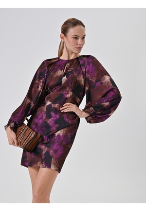 Korte mouw jurk in een donker bloemenpatroon met paarse en bruine tinten, met een getailleerde pasvorm en pofmouwen. Geaccentueerd met een kleine bruine handtas.