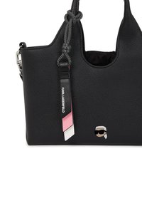 Black leather handbag featuring a textured finish, a knotted handle, a decorative strap with pink and white accents, and a logo detail.