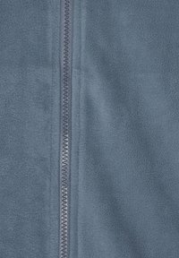 Fleece bunda v středně modré barvě s dlouhým zipem a hladkou, jemnou texturou. Obsahuje plochý šev podél zipu.