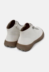 Stivaletti in pelle bianca con lacci grigi, suola in gomma marrone e un design semplice e arrotondato. Presentano un leggero tacco e una suola testurizzata.