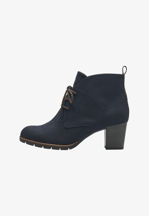 Bottine en nubuck marine avec un bout arrondi, semelle plate et un talon bloc de 6,5 cm. Présente des lacets contrastants et des détails cousus.