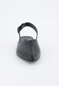 Scarpa slingback in pelle nera con punta affilata, suola piatta e una piccola fibbia sulla cinghia alla caviglia. Texture liscia e dettagli di cucitura minimi.