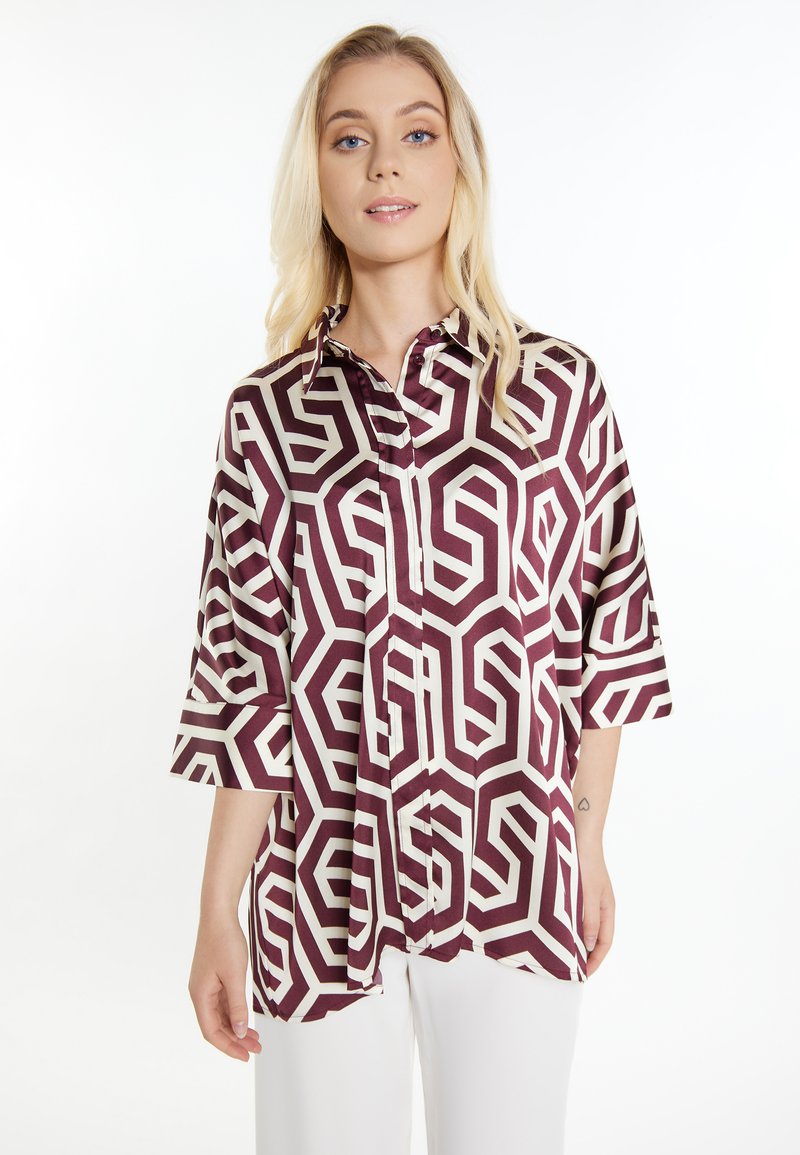 Blusa a maniche lunghe in tessuto geometrico color bordeaux, con colletto e chiusura a bottoni frontale, dalla vestibilità comoda. Texture liscia.