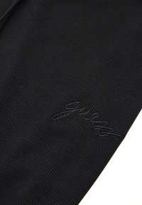 Black ribbed fabric with an embroidered brand logo. Features a smooth texture and consistent pattern throughout.