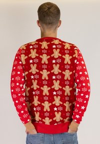 Red sweater featuring gingerbread men, snowflakes, and stars pattern; ribbed cuffs and hem; soft texture, festive design.