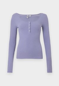 Ribbede langermede topp i lys lavendel, med scoop-hals og tre frontknapper, med en tettsittende silhuett og myk tekstur.