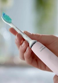 Philips Sonicare elektrische tandenborstel met een roze handvat, witte accenten en een blauwgroene borstelkop. Ergonomisch ontwerp met aan/uit-knop.