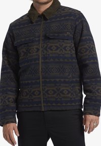 Navy and brown patterned jacket with a zip front, two chest pockets, and a fur-lined collar. The material appears textured and warm.