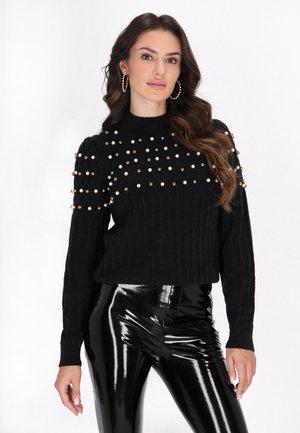 Sort ribbet sweater med rund halsudskæring og prydet med guld- og hvide perler. Sæt sammen med skinnende sorte højtaljede bukser.