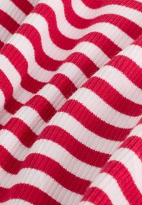 Tessuto a righe orizzontali rosso e bianco con fibbri, che mostra pieghe e texture in primo piano.