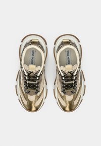 Sneakers met een mix van metallic goud en beige materialen, een gestructureerde slangenprint, zwarte veters en een dikke bruine rubberen zool.