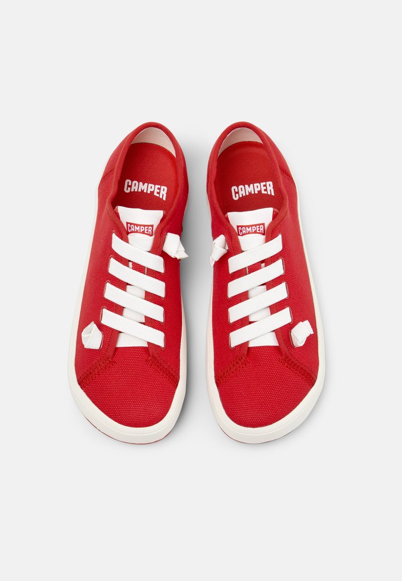 Zapatillas de lona rojas con cordones blancos, con puntera redondeada y superficie texturizada. Nombre de la marca "CAMPER" mostrado de forma destacada en la lengüeta.