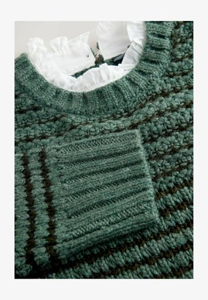 Tumes roheline kudum, millel on tekstuuriline muster. Sisaldab ümarat kaelaauku ja valget volangi kaelust. Includes a patch pocket.