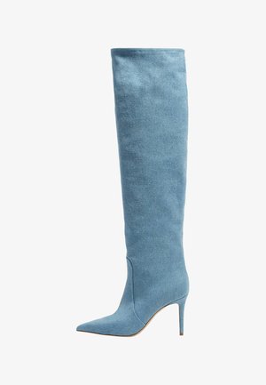 Botte haute pour femme en denim bleu clair avec bout pointu et talon fin sur fond blanc.