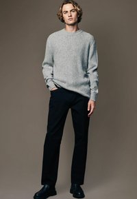 Gray ribbed knit sweater, black straight-leg trousers, and black shoes. Simple design, relaxed fit, and textured fabric detail.