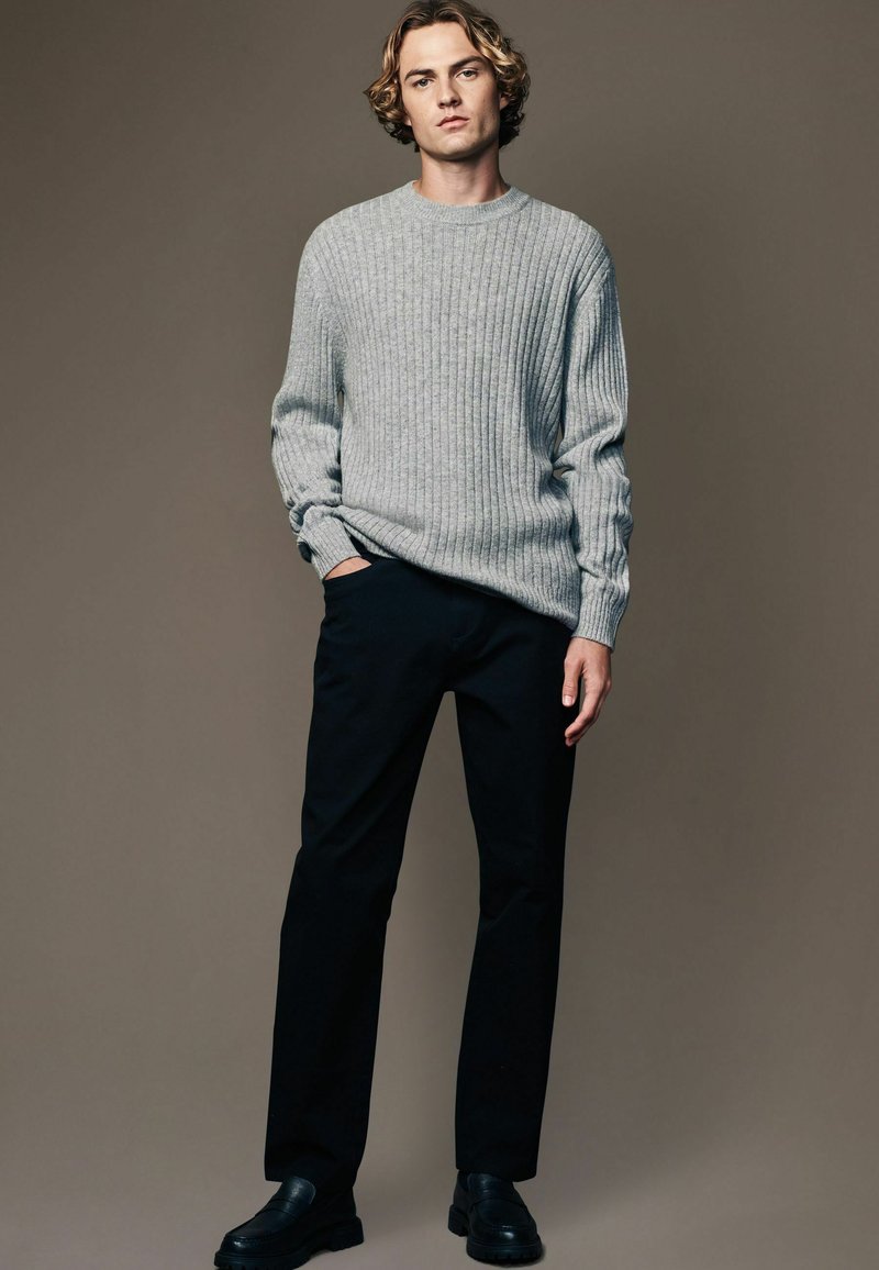 Gray ribbed knit sweater, black straight-leg trousers, and black shoes. Simple design, relaxed fit, and textured fabric detail.