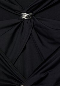 Schwarzes Kleidungsstück mit gerafftem Stoff, das ein verdrehtes Design und einen glänzenden silbernen Ringakzent in der Mitte aufweist. Glatte Textur, figurbetont.