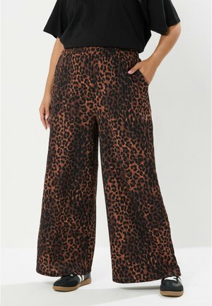 Pantalones de pierna ancha con estampado de leopardo en tejido marrón y negro, cuentan con una cintura elástica y bolsillos laterales. Combinados con zapatillas negras.