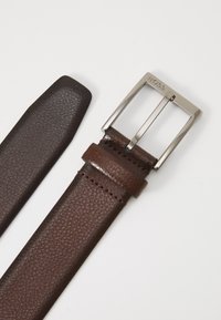 Ceinture en cuir marron avec une finition texturée, dotée d'une boucle en argent et d'un marquage. Comprend une extrémité effilée lisse et des accents cousus.
