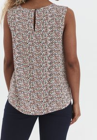 Top senza maniche con motivo floreale e apertura a goccia sul retro, caratterizzato da uno sfondo nero e piccoli fiori rosa, bianchi e verdi. Tessuto morbido, orlo arrotondato.