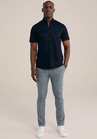 Cămașă bleumarin cu mânecă scurtă și capse, asortată cu pantaloni texturați gri deschis și adidași albi. Design simplu și ajustat.