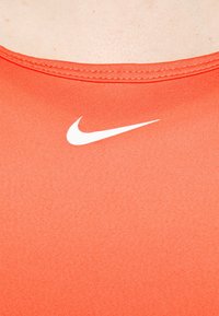 Rotes Nike-Tanktop mit rundem Halsausschnitt, glatter Stoffoberfläche und einem kontrastierenden weißen Swoosh-Logo im Brustbereich.