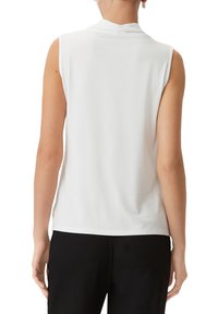 Top bianco senza maniche realizzato in tessuto morbido, con colletto alto e vestibilità ampia, caratterizzato da un design semplice senza motivi o dettagli visibili.