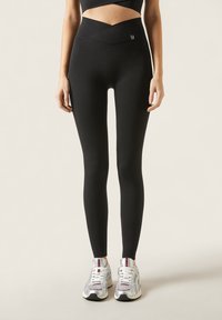 Sorte høj talje leggings med et kryds-front bælte design. Fremstillet af strækbart stof, de har en glat tekstur og en tætsiddende silhuet.