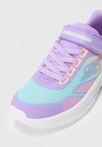 Purple and light blue athletic shoe with mesh upper, pink accents, and a white rubber sole. Features laces and a branded strap.