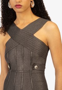 Metaalgrijze jurk met gekruiste ribbelachtige banden en op maat gemaakte details. Bevat knopenaccenten ter hoogte van de taille. Gladde textuur, aansluitend ontwerp.